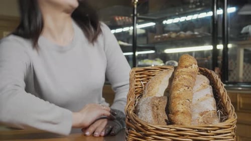Young Woman Smiling at Basket of Bread in Bakery