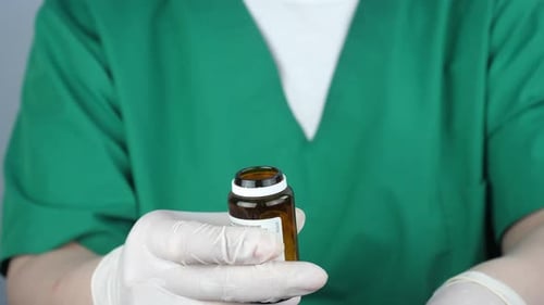 Medical Professional Opens Pill Bottle, Pours Medicine
