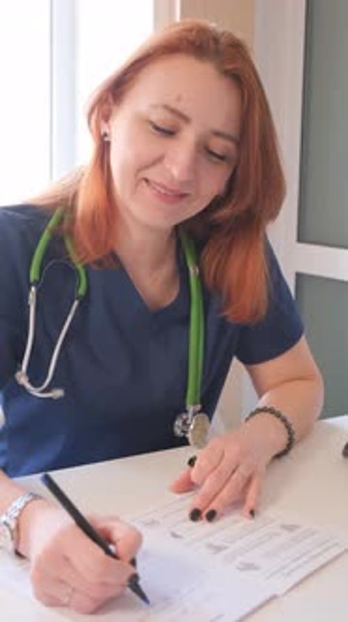 Smiling Doctor Filling Out Medical Form at Desk