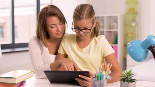 Mother and Daughter Using Tablet at Desk