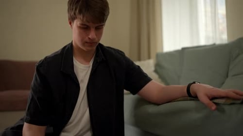 Un jeune homme est assis avec une fille dans un salon, il l'aide alors qu'ils travaillent ensemble sur une tâche