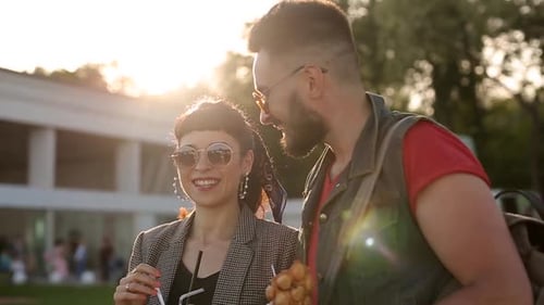 Casal hippie estiloso caminhando comendo sorvete e waffles rindo no parque da cidade, jovem romântico