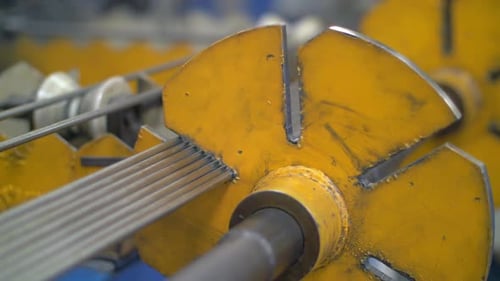 Industriemaschine, die eine Metallstange in der Fabrikwerkstatt hält. Automatisierte Geräte zur Bearbeitung von Metallschweiß...