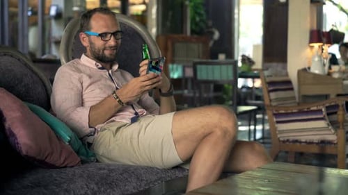 Man on couch with phone and beer