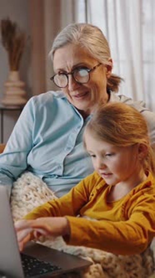 Grandmother and Granddaughter Using Laptop Together Indoors