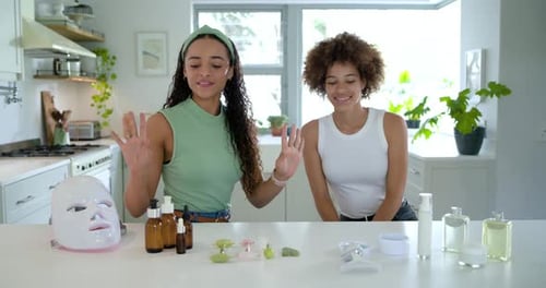 Amigas sentadas en la cocina, presentadora izquierda hablando ante la cámara y probando el suero en la muñeca