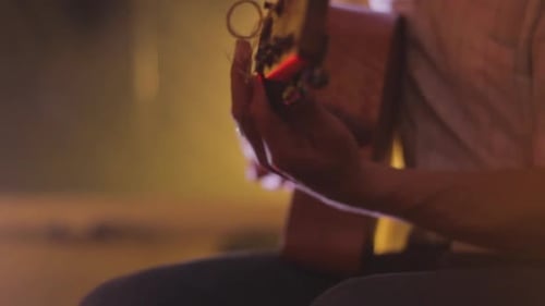 Person Plays Guitar Indoors in Warm Lighting