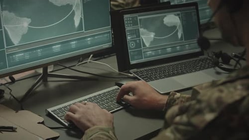 Man in Camouflage Working at Computer with World Map