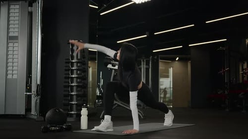 Young Woman Stretching at the Gym on a Mat