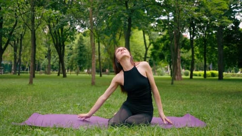 an experienced female instructor meditates in the park practices yoga does stretching and exercises