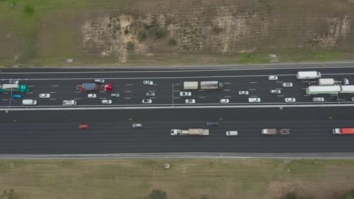 Static aerial perspective looking directly down over busy highway with traffic moving slowly on one