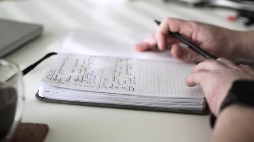 Hand Writing in a Notebook at Desk