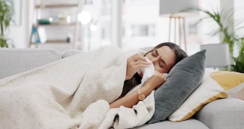 Mujer enferma, manta y gripe en el sofá por el frío, las alergias y el virus del invierno en el salón