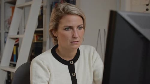 Smart young and confident business woman working hard at her computer behind her desk in a modern cl