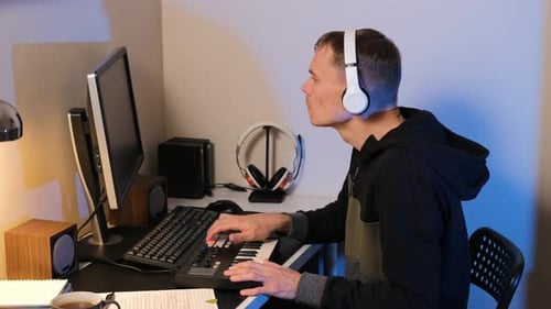 Young adult playing keyboard at desk in room