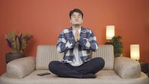 Man Meditating on Sofa Indoors