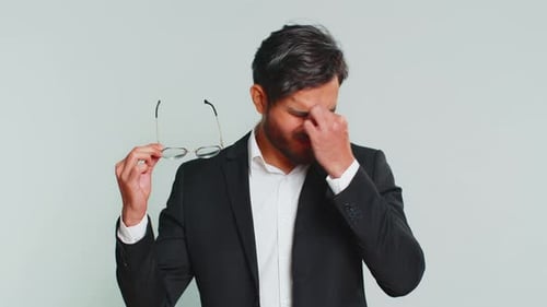 Man Takes off Glasses and Rubs Eyes