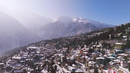 stunning view of a snow-covered mountain town nestled among towering peaks and lush forests