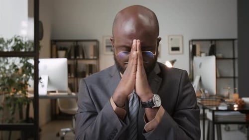 African American Man Sitting with his Hands Folded in Prayer in Office