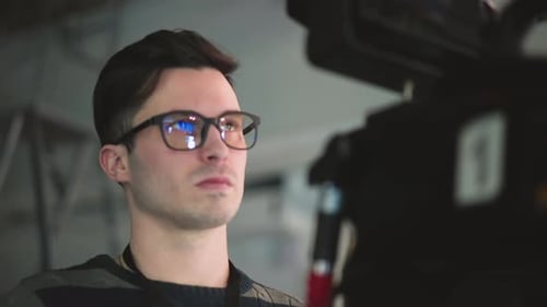 Closeup of Man with Glasses Focused on Professional Camera in Broadcast Studio