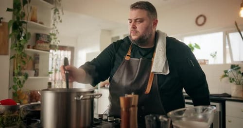 Chef stirs pot in kitchen.
