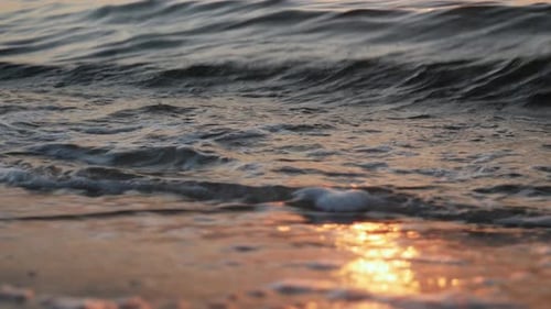 Schaumige Wellen, die bei Sonnenuntergang am Ufer rollen, enge Sicht