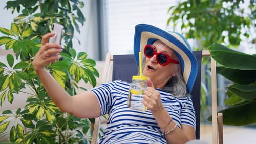 Senior woman taking a selfie with lemonade indoors