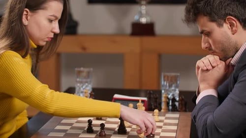 Frau mit gelbem Pullover spielt Schach gegen Geschäftsmann. Aufnahme aus der Hand