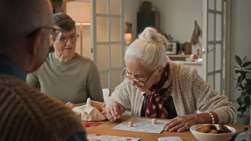 Three Adults Playing Bingo at a Table Indoors