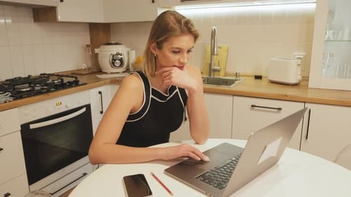 Woman Uses Laptop in Bright Modern Kitchen