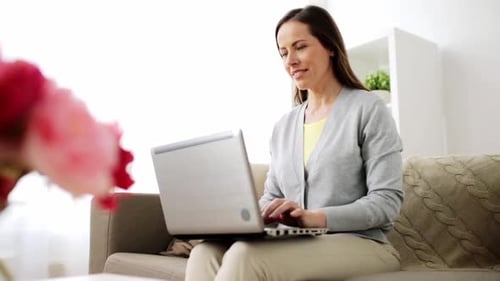 Woman using Laptop Computer on a Couch at Home