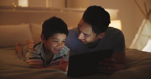 Dad and Child Enjoy Tablet Time on Bed