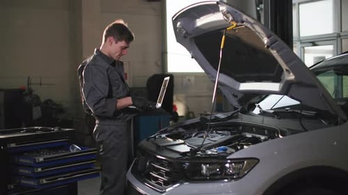 Maintenance of Machine a Young Male Specialist with a Laptop in His Hands Diagnosis Vehicle at