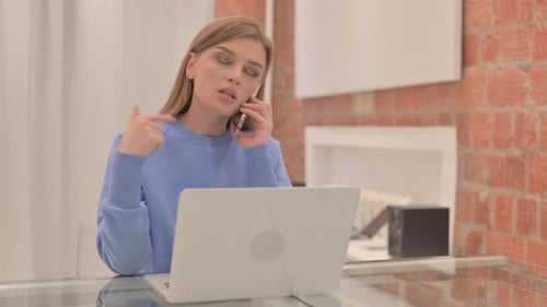 Frustrated Woman on Smartphone at Laptop