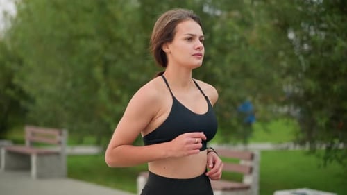 Aerial View of Woman Jogging in Park with Benches and Green Trees Background
