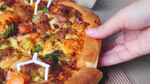 Hand Taking a Slice of Pizza from Box