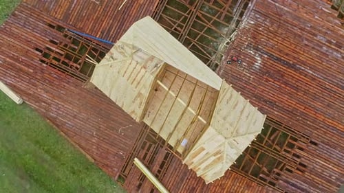 rising aerial footage of a wooden plateau and house under construction with a trussed frame in a fo