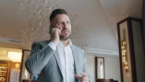Businessman Talking on Mobile Phone in Hotel Lounge