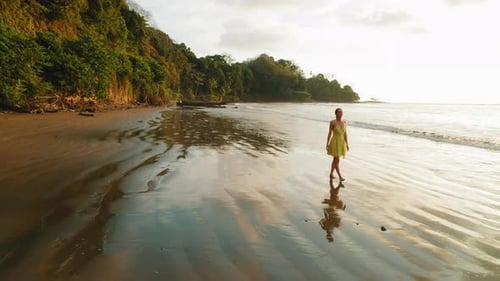Woman enjoying golden hour while walking on secluded sandy each in Costa Rica