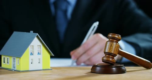 Gavel and House Model in Front of Writer
