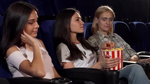 Young Woman Frustrated As Friends Sneak Her Popcorn at the Cinema