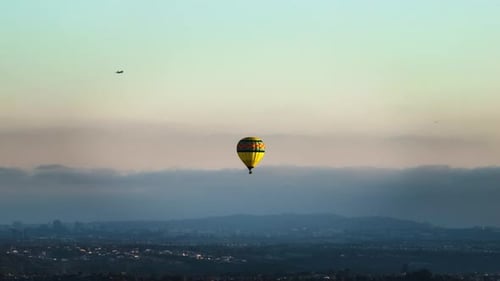 Hot Air Ballooning Above City at Sunrise