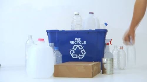 Hand Placing Bottles in a Recycling Bin