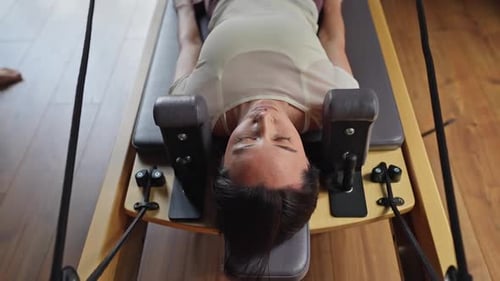 Woman Doing Pilates Exercise with Trainer