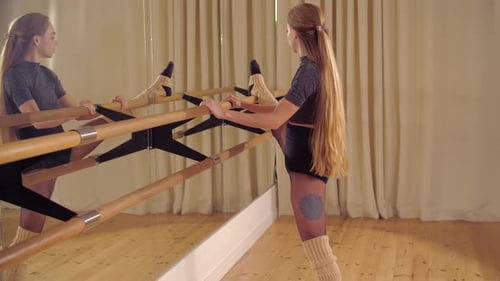 Woman Stretching at Ballet Barre in Dance Studio