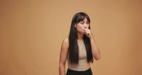 Hispanic Latin Woman Coughing in Yellow Shirt on Blue Background in Studio Health Care Medicine