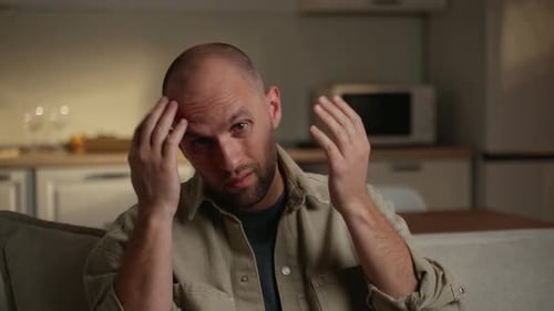 Man Rubbing Head and Looking Frustrated
