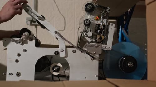 Trabalhador usando aplicador de etiquetas para rotular garrafas de sidra na cervejaria