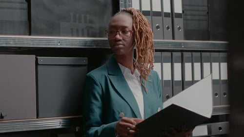 Professional Woman Holding File Standing by Shelves