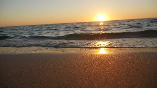 Sunrise on the sand beach in slow motion, waves crashing on the shore.